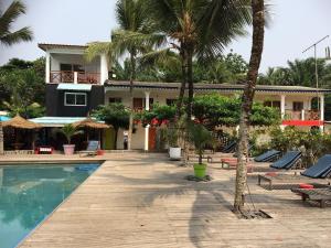 un complexe avec une piscine et des palmiers dans l'établissement Hôtel du Phare, à Kribi