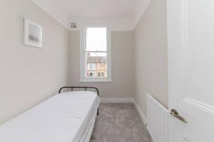 Habitación blanca con cama y ventana en Stylish & Spacious 3-Bed House, Parking and Garden, en Finchley