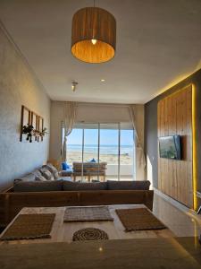 a living room with a couch and a view of the beach at Sidi Rahal Blue View, Piscine & mer sans vis-à-vis in Sidi Rahal