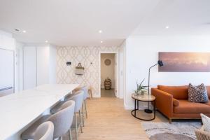 Newlands Peak Luxury Suite في كيب تاون: غرفة معيشة مع أريكة برتقالية وكراسي