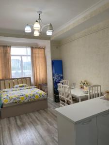 1 dormitorio con 1 cama, cocina y mesa en Kojomkul, en Bishkek