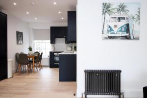 a kitchen with black cabinets and a table with chairs at Heart of Bath: Kingsmead Apartment in Bath