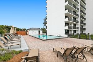 a patio with chairs and a swimming pool in front of a building at One Seagrove Place 0908 in Santa Rosa Beach