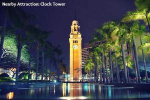 a clock tower in front of a building with palm trees at Primo Guesthouse in Hong Kong