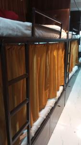 a row of bunk beds with orange curtains on them at Golden View Dormitory in Mumbai