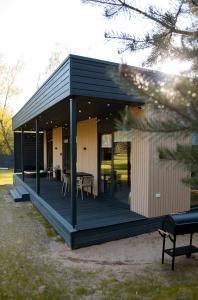 een zwart huis met een terras met tafels en stoelen bij Chill Hill Kalviai 