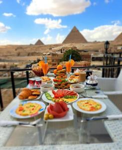 Royal Golden Pyramids Inn في القاهرة: طاولة مع أطباق من الطعام مع الأهرامات في الخلفية