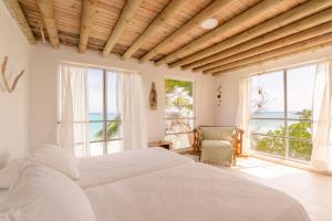 a bedroom with a white bed and large windows at Casa Tinti in Tintipan Island