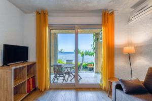 a living room with a television and a sliding glass door at Résidence Marine de Palumbare in LʼÎle-Rousse