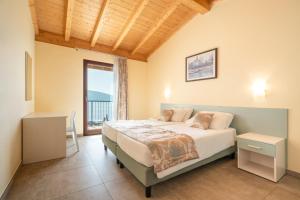 een slaapkamer met een bed en een groot raam bij Residence Dany appartamenti con cucina vista lago piscina e parcheggio in Gargnano
