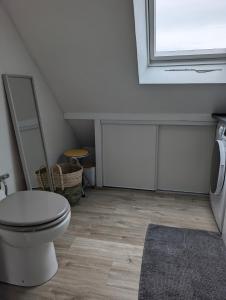a white bathroom with a toilet and a window at Le Cosy in Lanvallay
