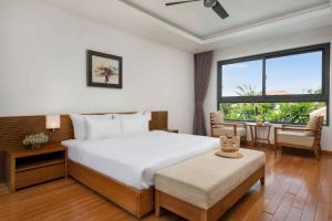 Schlafzimmer mit einem Bett, einem Tisch und einem Fenster in der Unterkunft Ocean Beach Resort Da Nang in Đà Nẵng