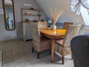 a dining room with a wooden table and wicker chairs at Le Cosy in Lanvallay