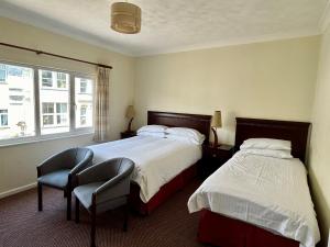 a bedroom with two beds and a chair and a window at Bay View - Seafront, Sandown - FREE CAR FERRY in Sandown