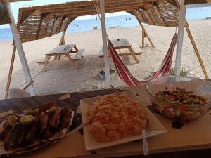 een tafel met een bord eten op het strand bij Sea sound Camp in Nuweiba‘ el Muzeinah
