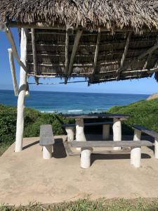 einem Picknicktisch und einer Bank vor dem Meer in der Unterkunft Bonito Bay in Cabo Nhabacal