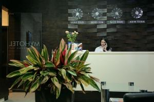 a woman talking on a cell phone behind a counter with a plant at My Hotel Yerevan in Yerevan