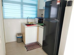 uma cozinha com um frigorífico preto e um lavatório em Mutiara Melaka Beach Resort em Tangga Batu