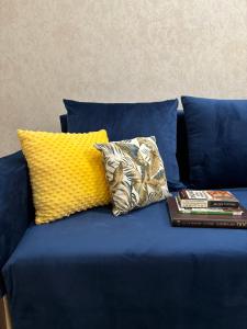 Un sofá azul con dos almohadas y un libro. en ЖК ALPAMYS, en Astana