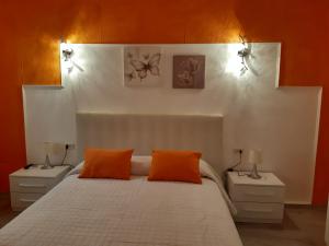 ein Schlafzimmer mit einem weißen Bett und orangefarbenen Kissen in der Unterkunft Appartamento Giardino in Domus de Maria