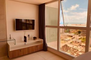 - un salon avec une télévision et une grande fenêtre dans l'établissement Flat Vista mar & Estacionamento, à Cabedelo