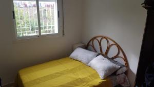 ein Schlafzimmer mit einem Bett mit einer gelben Decke und einem Fenster in der Unterkunft Mouad house in Martil