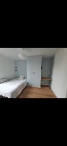 a bedroom with a white bed and a white cabinet at Chambres disponibles - Saint Denis City Center Porte de Paris - Métro 13 - RER D - Ligne H - Tramway 1-5-8 in Saint-Denis