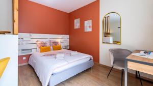 - une chambre avec des murs orange, un lit et un bureau dans l'établissement Le Nid - hébergement cosy, à Dijon