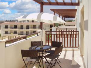 a balcony with a table and chairs and an umbrella at 2 bedrooms apartement with shared pool furnished terrace and wifi at Larnaca 2 km away from the beach in Tersephanou