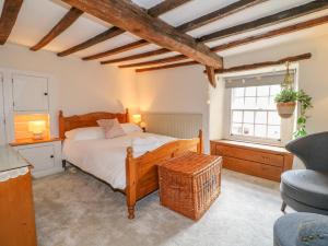 een slaapkamer met een bed, een stoel en een raam bij Jasmine Cottage in Matlock