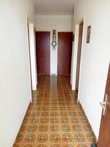 an empty hallway with a tile floor and doors at Apartman SunnySide in Rogoznica