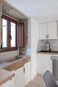 eine Küche mit weißen Schränken und einem Fenster in der Unterkunft Casa bajo con jardín LaFinca Finisterre in Kap Finisterre