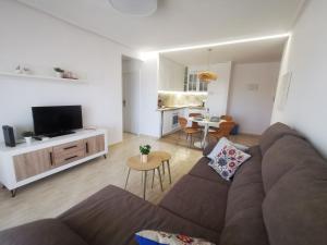 ein Wohnzimmer mit einem braunen Sofa und einer Küche in der Unterkunft Słoneczny Apartament Parque IV in La Mata