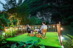 a man and woman sitting at a table in a garden at night at Hoang Minh Mountainside Villa in Ninh Binh