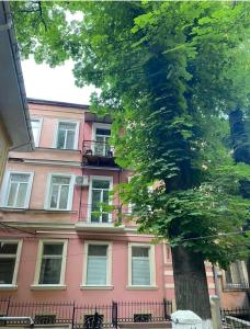 a pink building with a tree in front of it at Елисаветинская 15 in Odesa