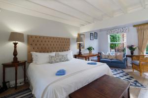 1 dormitorio con 1 cama blanca grande y 1 sofá en Fiddlewood Fields Guest House, en Grahamstown