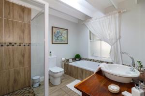 uma casa de banho com uma banheira, um WC e um lavatório. em Fiddlewood Fields Guest House em Grahamstown