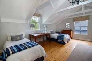 een slaapkamer met 2 bedden, een bureau en een raam bij Fiddlewood Fields Guest House in Grahamstown