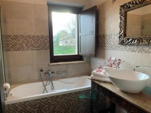 een badkamer met een bad, een wastafel en een raam bij Casa Raphael, Amandola in Amandola