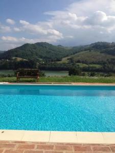 een blauw zwembad met een bank op de achtergrond bij Casa Raphael, Amandola in Amandola