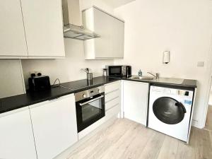 a kitchen with white cabinets and a washing machine at Modern Boutique Apartment Great Location in Golders Green
