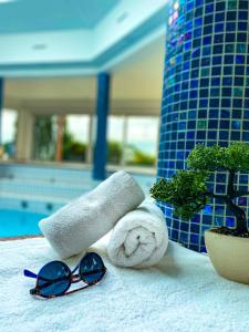 a towel and sunglasses sitting next to a pool at Hotel Römerstein - Die Wohlfühloase in Loipersdorf bei Fürstenfeld