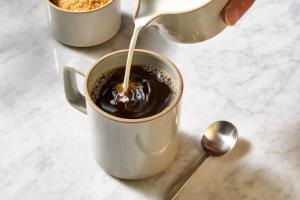 une personne verse du lait dans une tasse de café dans l'établissement TownePlace Suites Gaithersburg, à Gaithersburg