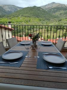 a table with plates and wine glasses on a deck at EL BALCÓN PANORÁMICO DEL TIÉTAR in Mijares