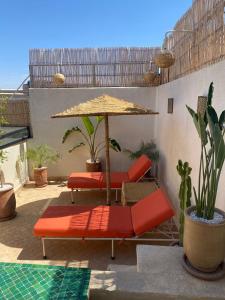 um pátio com uma mesa, cadeiras e um guarda-sol em Magnifique Riad Privatif Kasbah em Marrakech