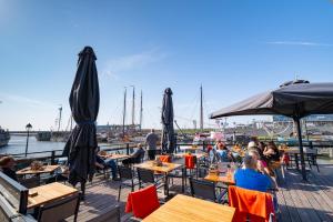 a group of people sitting at tables on a dock with boats at Hotel Zeezicht in Harlingen