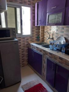 una cocina con armarios morados y fregadero en fleur, en Dakar