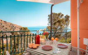 a table with plates and a bottle of wine on a balcony at Pascià Madonna Rocca in Taormina