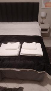 ein Bett mit einer schwarzen Decke und weißen Handtüchern darauf in der Unterkunft Asturias in Presidencia Roque Sáenz Peña