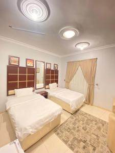 a bedroom with two beds and a mirror at أجــنــحــة وتــيــن in Al Madinah